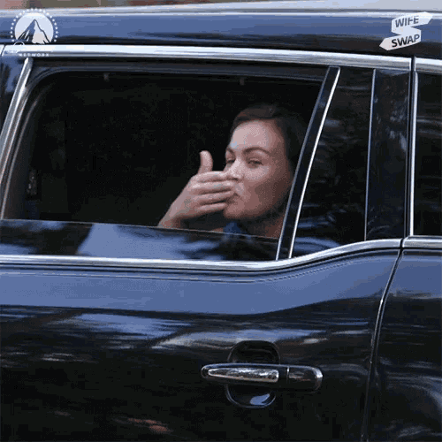 a woman sitting in a car with a wife swap sticker on her window