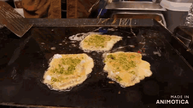 three eggs are being cooked on a griddle with the words made in animotica on the bottom right