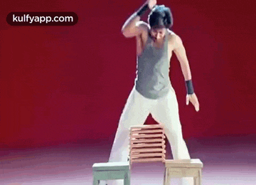 a man is standing on top of a stack of chairs on a stage .