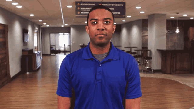 a man in a blue shirt is standing in front of a sign for vibrant students