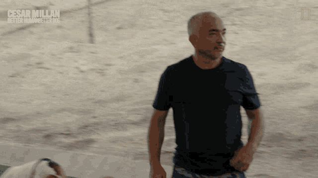a man stands in front of a sign that says cesar millan better human for dogs