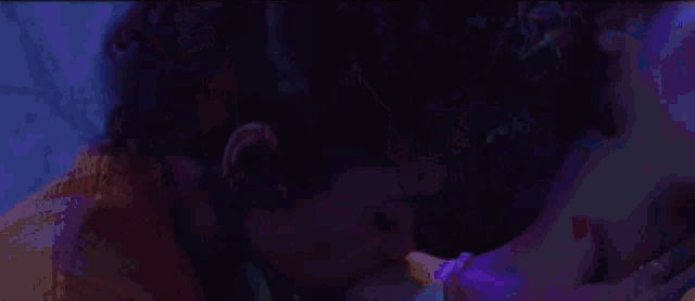 a person is standing in a dark room with a purple light shining on them