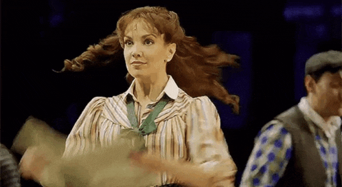 a woman in a striped shirt is dancing on a stage in front of a group of people .