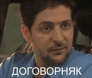 a man wearing glasses and a brown jacket has the word договорняк on the bottom right