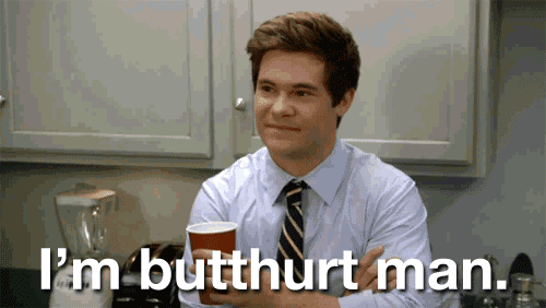 a man in a suit and tie is holding a cup of coffee and says i 'm butthurt man