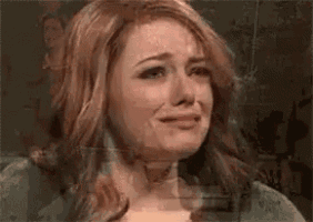 a woman is crying in front of a mirror with a blurry background .