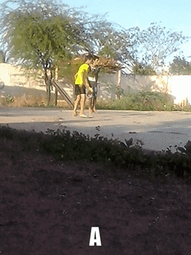 a man in a yellow shirt is walking down a sidewalk with the letter a above him