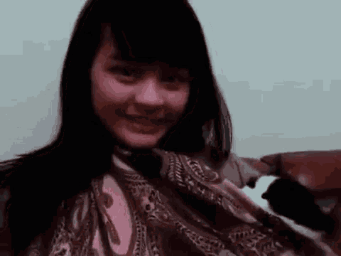 a woman is sitting on a couch holding a cat in her arms .