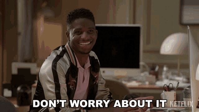 a man sitting at a desk with the words " do n't worry about it " on the screen