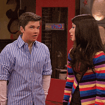 a boy in a blue striped shirt stands next to a girl in a colorful striped cardigan