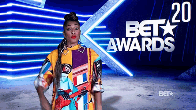 a woman stands in front of a bet awards poster
