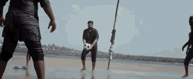 a man is kicking a soccer ball on the beach .