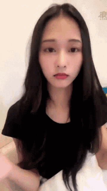 a woman with long black hair is sitting on a bed