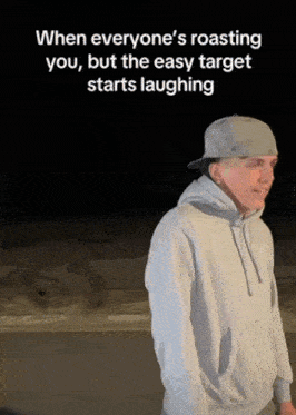a man wearing a hat and a hoodie is standing in the dark