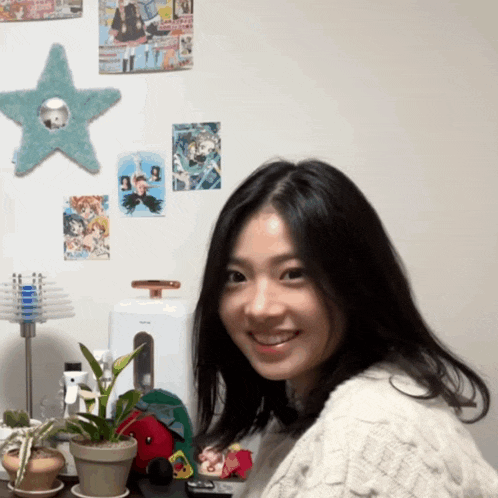 a woman stands in front of a wall with posters on it including one that says ' tokyo ghoul '