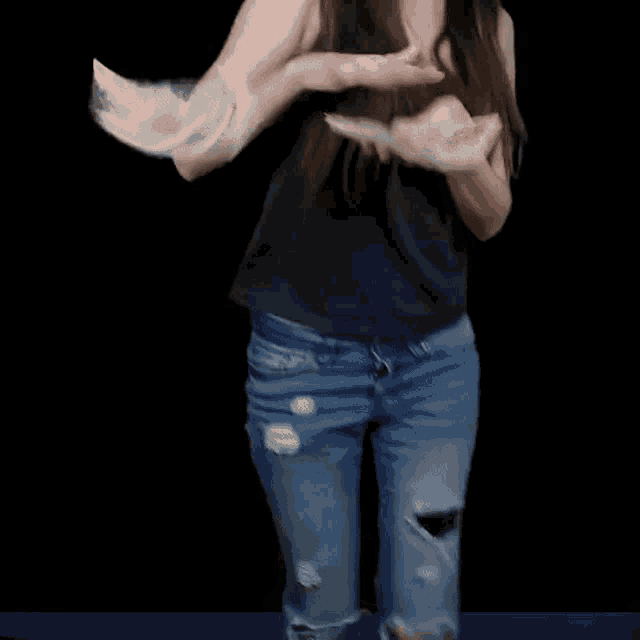 a woman is dancing in front of a black background .