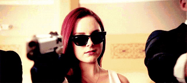 a woman with red hair is holding a gun in front of her face