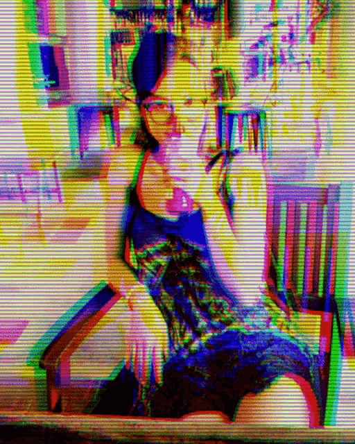 a woman in glasses sits in a chair in a colorful image