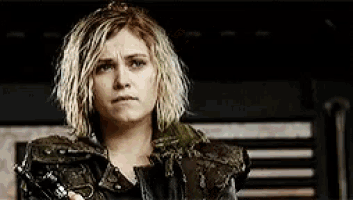a woman with blonde hair and dreadlocks is wearing a black leather jacket .