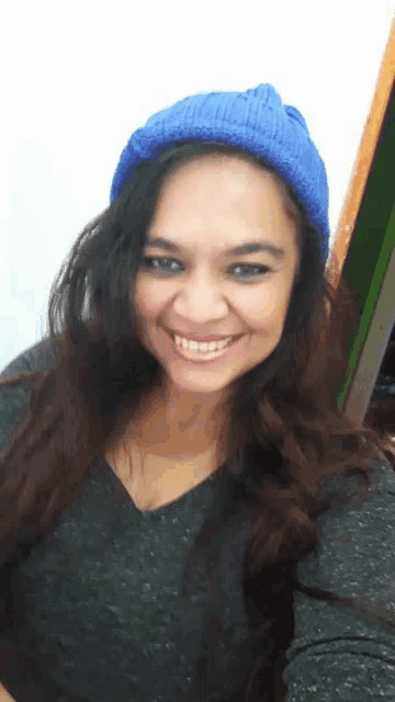 a woman wearing a blue hat and a grey shirt smiles