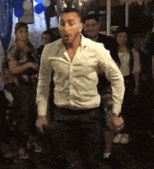 a man in a white shirt is dancing in front of a crowd of people