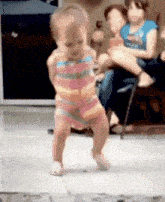 a little girl is dancing on a stage in front of a group of people