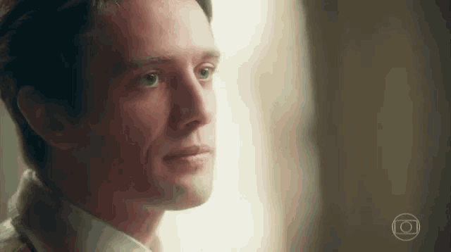 a close up of a man looking out a window with a circle in the corner