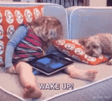a little girl laying on a couch with a tablet and a dog laying next to her saying wake up ..