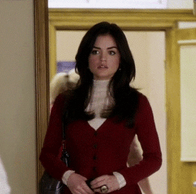 a woman wearing a red cardigan is standing in a hallway