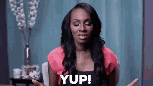 a woman in a pink top is sitting in a chair and says yup !