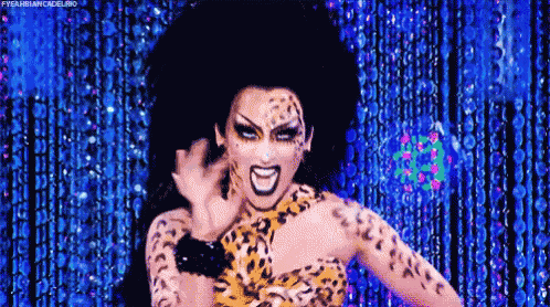 a drag queen is wearing a leopard print dress and making a funny face on a stage .