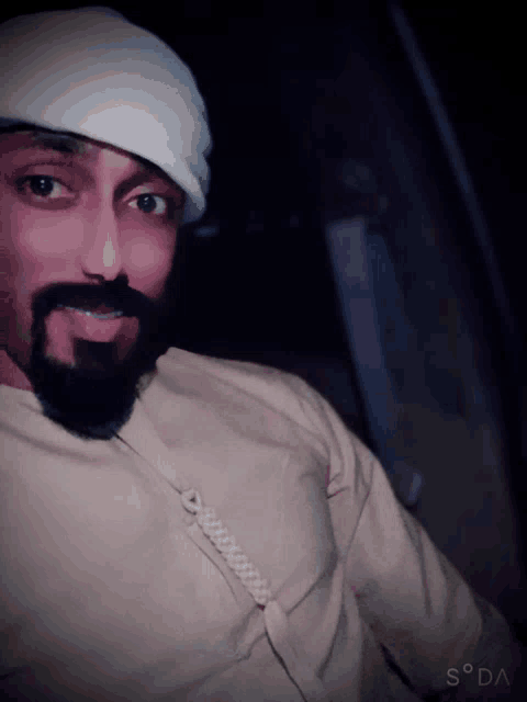 a man with a beard wearing a white hat and a shirt that says soda on the bottom