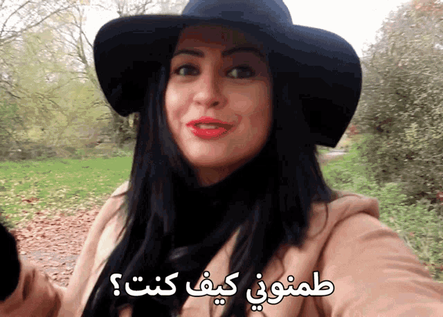 a woman wearing a black hat and a tan coat with arabic writing on the bottom