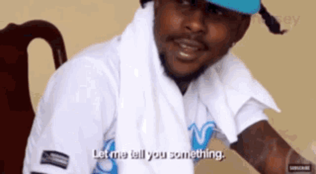 a man wearing a blue hat and a white shirt says let me tell you something