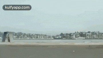 a car is driving down a highway next to a body of water and a city .
