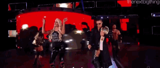 a group of wrestlers are standing on a stage in front of a red background .
