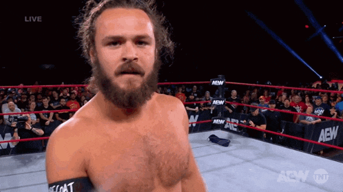 a man with a beard is standing in a wrestling ring with aew written on the side