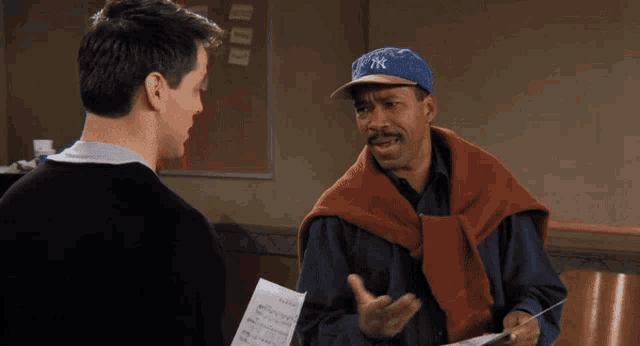 a man wearing a new york yankees hat talks to another man