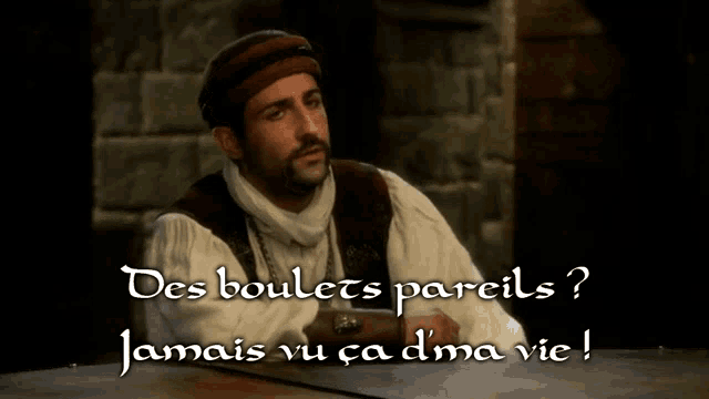 a man with a beard is sitting at a table with the words des boulets pareils jamais vu ca dma vie