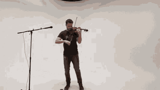 a man is playing a violin in front of a microphone in a studio .