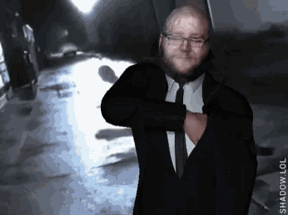 a man in a suit and tie is standing in a dark room with the word shadow on the bottom