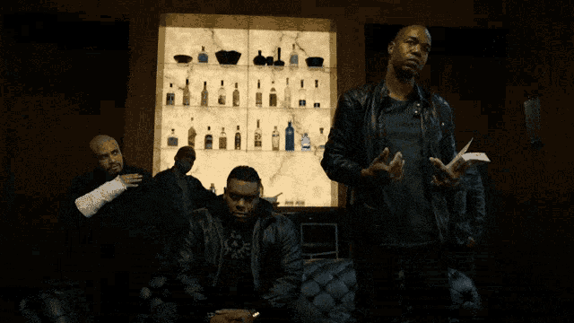 a man holding a piece of paper stands in front of a shelf full of bottles