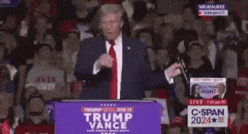 a man in a suit and tie is standing at a podium giving a speech in front of a crowd .