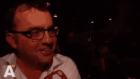 a man wearing glasses and a white shirt is smiling .