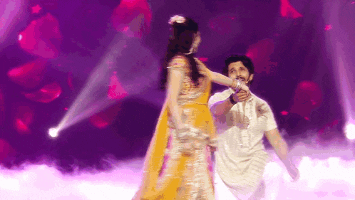 a man and a woman are dancing on a stage in front of a purple background .