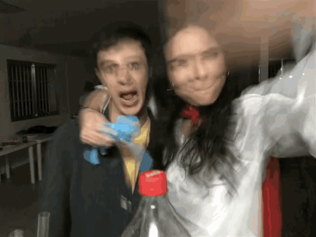 a man and a woman are posing for a picture with a bottle of coca cola in front of them