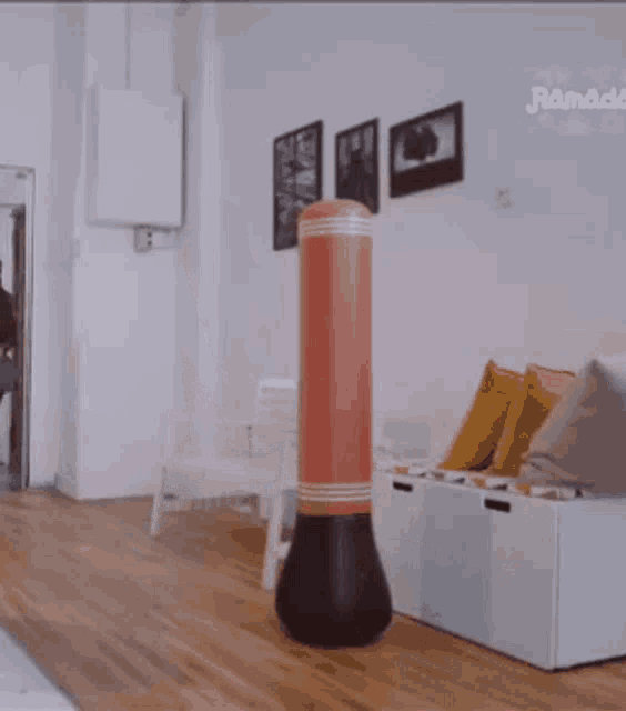 a woman in a hijab is dancing in front of a punching bag in a living room