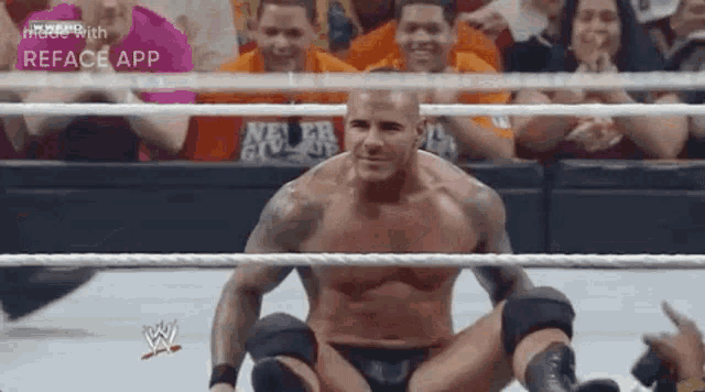 a wrestler is kneeling down in a wrestling ring with his legs crossed .