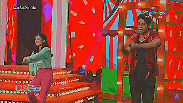 a man and a woman are dancing on a stage with a colorful background .