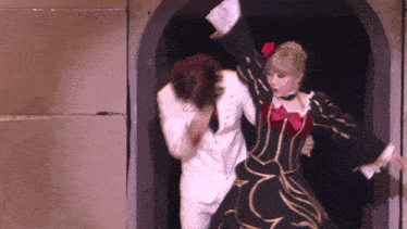 a man in a white suit and a woman in a black and gold dress are dancing together